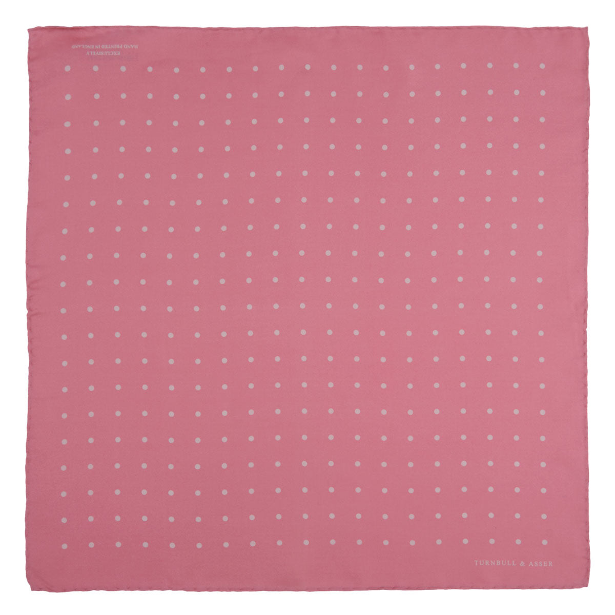 View 2 of product The Rose and White Spot Silk Pocket Square by Turnbull & Asser features rose pink silk with white polka dots and Turnbull & Asser branding in the corner—a refined accessory for any navy suit collection.