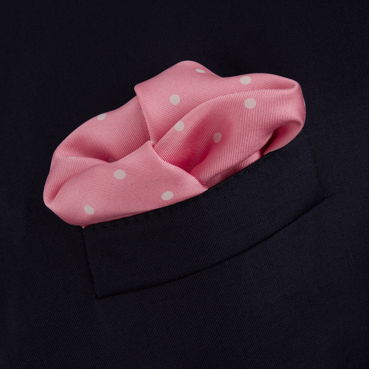 View 4 of product The Rose and White Spot Silk Pocket Square by Turnbull & Asser features rose pink silk with white polka dots and Turnbull & Asser branding in the corner—a refined accessory for any navy suit collection.