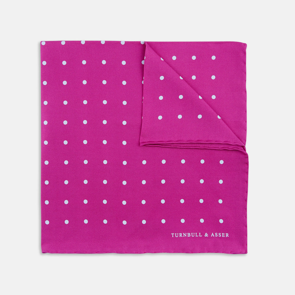 The Fuchsia Spot Silk Pocket Square by Turnbull & Asser features bright fuchsia silk with evenly spaced white spots and the brand’s name in one corner. A classic accessory, it is shown with one corner folded over.