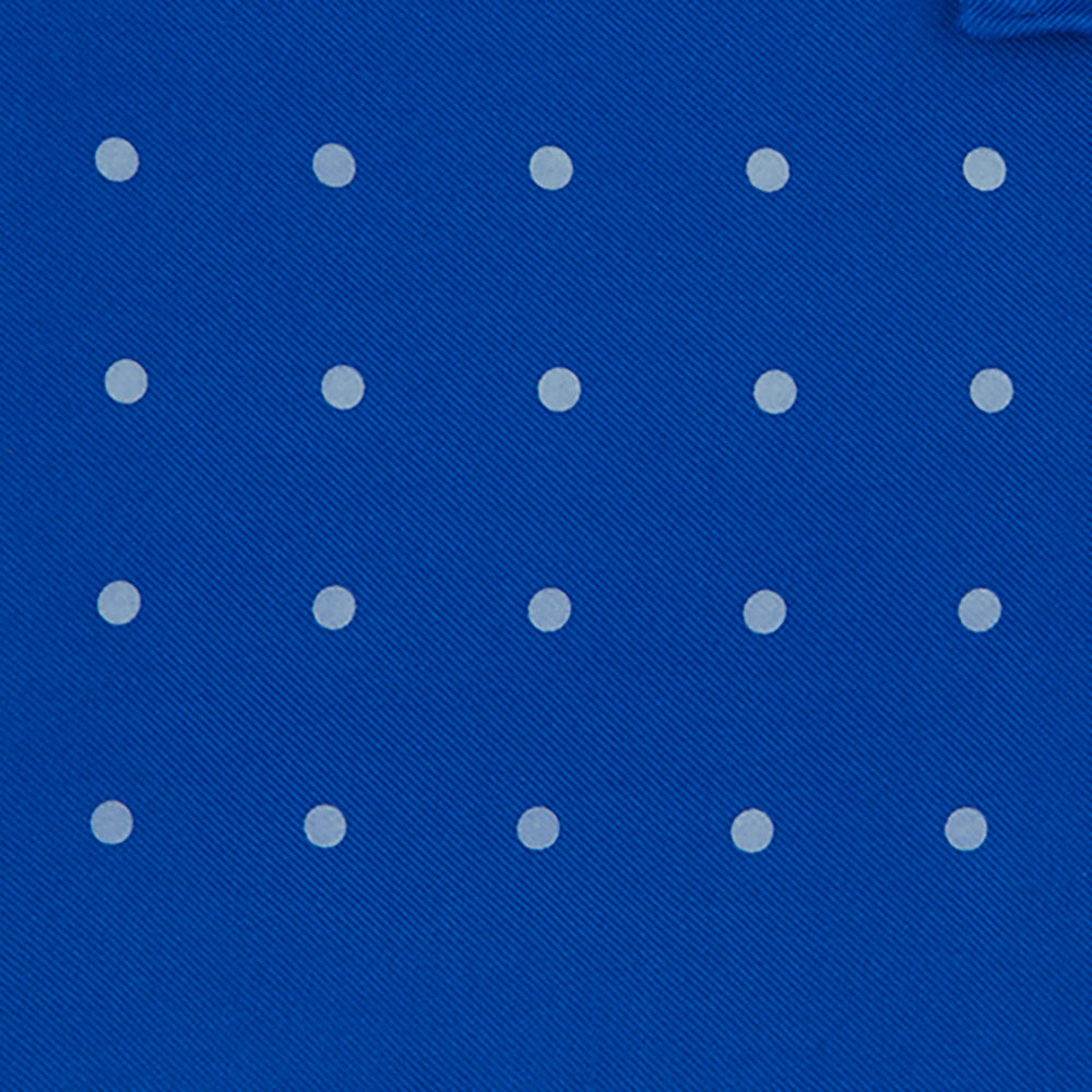 The Royal Blue Spot Silk Pocket Square by Turnbull & Asser features evenly spaced white polka dots and a branded corner, making it the perfect accessory to add flair to pinstripe suits.