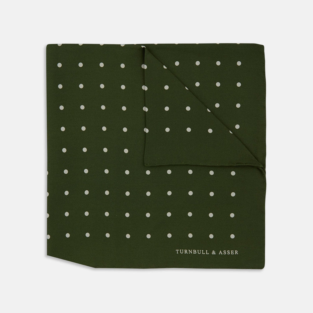 The Turnbull & Asser Olive Spot Silk Pocket Square features white polka dots, the brand’s logo in one corner, and a stylishly folded tip for a dapper finish.