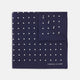 The Navy Spot Silk Pocket Square by Turnbull & Asser features a white polka dot pattern and is neatly folded at one corner, with the brand name printed in white on the lower right—perfect for pairing with pinstripe suits.