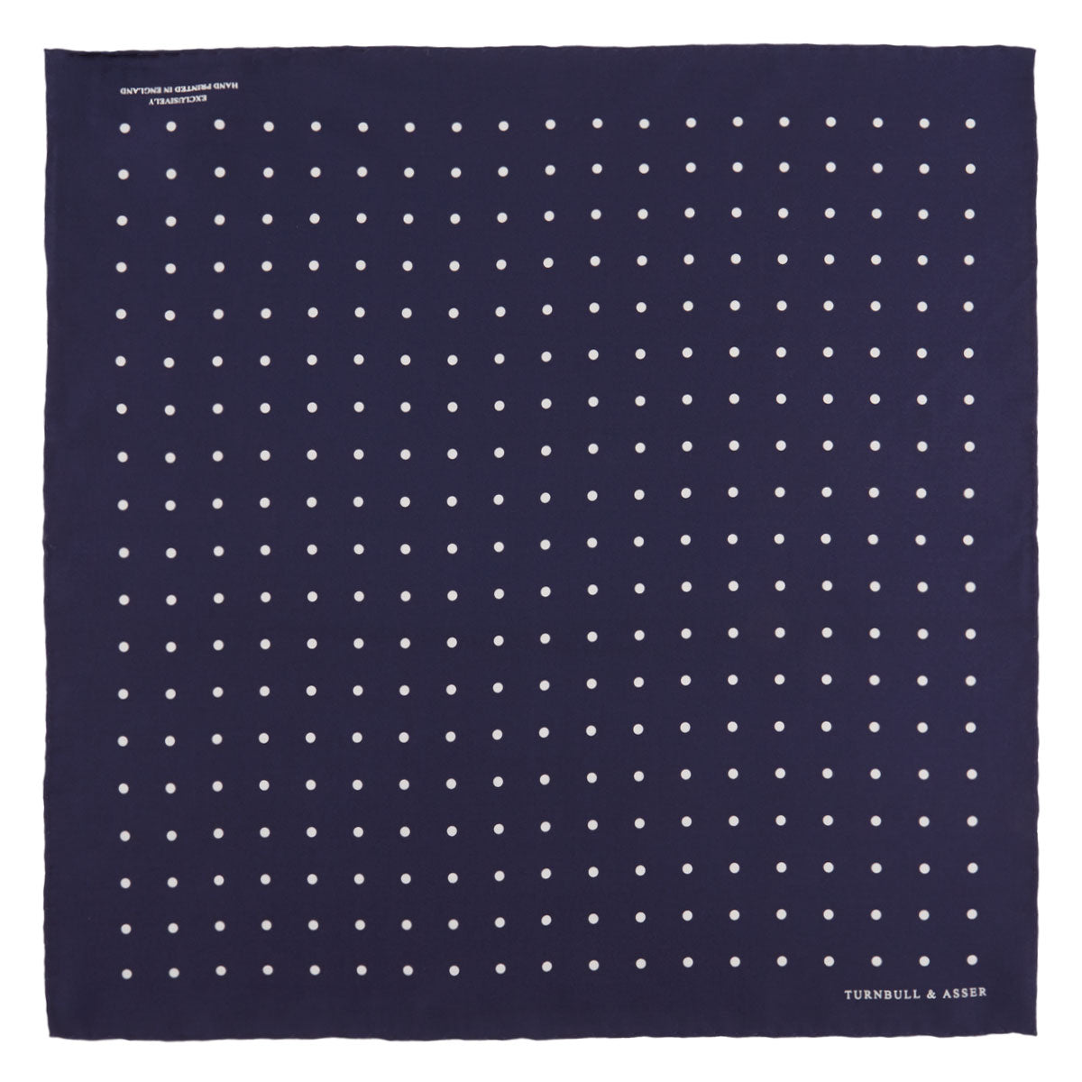 View 2 of product The Navy Spot Silk Pocket Square by Turnbull & Asser features a white polka dot pattern and is neatly folded at one corner, with the brand name printed in white on the lower right—perfect for pairing with pinstripe suits.