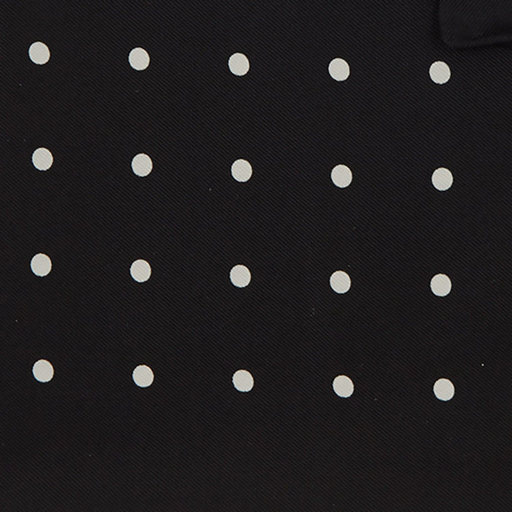 The Black Spot Silk Pocket Square by Turnbull & Asser features classic white polka dots on black silk, with the brand name printed in one corner and a stylish folded design.