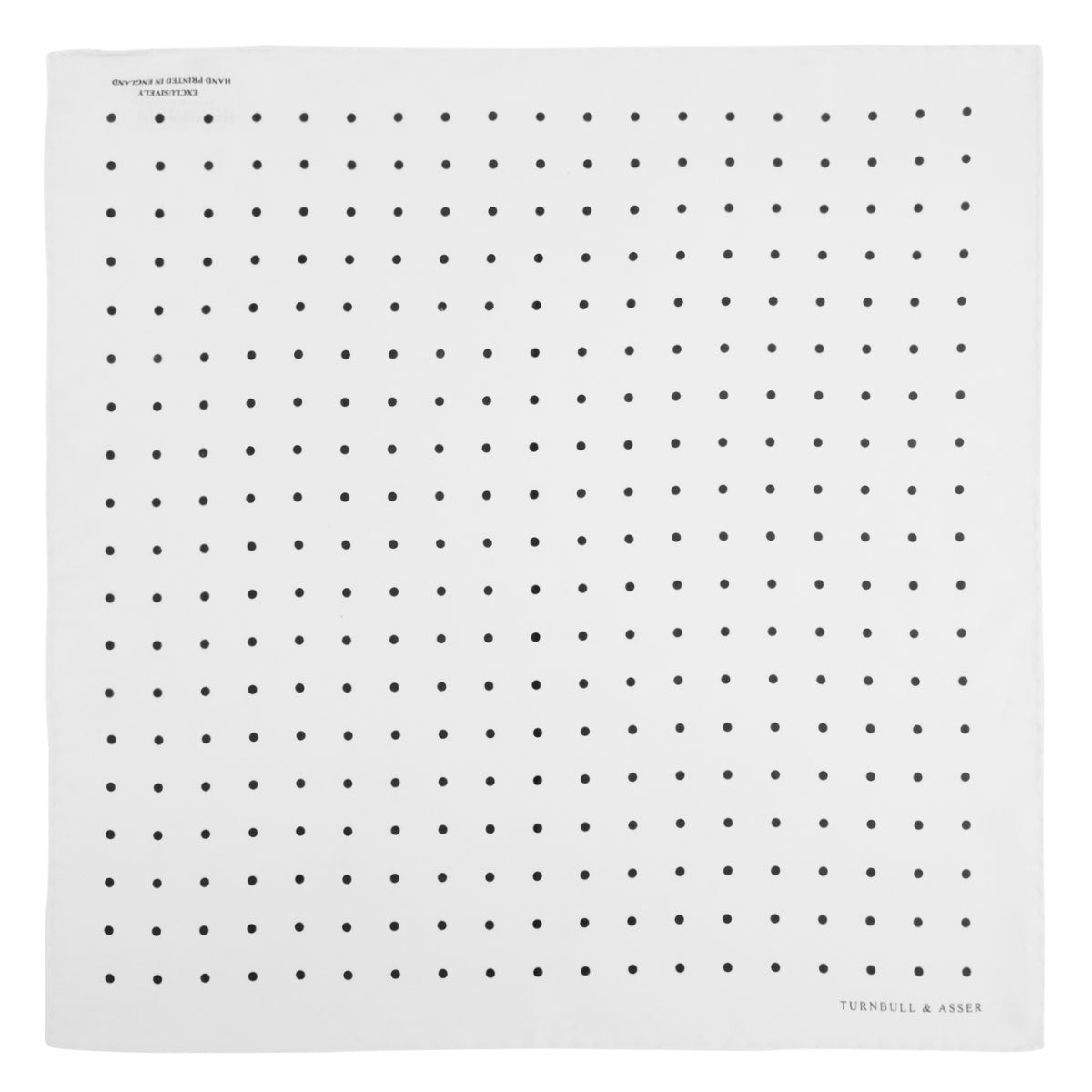 View 2 of product The Turnbull & Asser White and Black Spot Silk Pocket Square for men features evenly spaced black dots, a partial corner fold, and the brand name printed in black in the lower right corner.