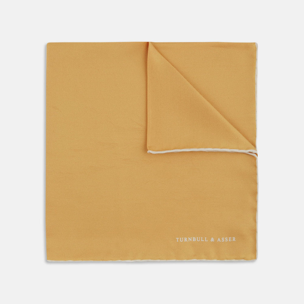 The Gold and White Piped Silk Pocket Square by Turnbull & Asser features neat white edging and TURNBULL & ASSER printed in one corner—a timeless silk accessory for any wardrobe.