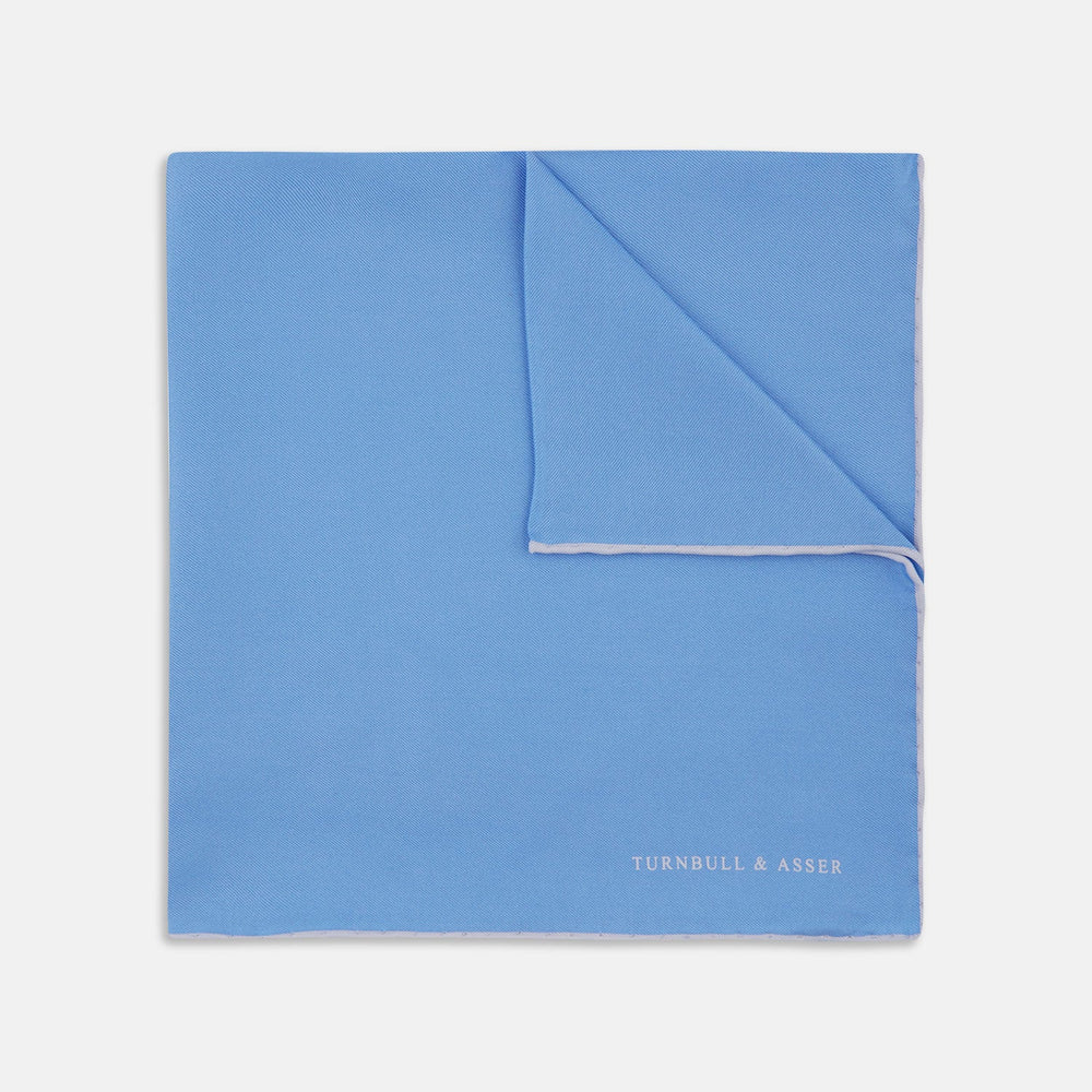 A Blue and White Piped Silk Pocket Square by Turnbull & Asser, neatly folded with the brand name in white on the lower right corner, displayed against a plain white background.