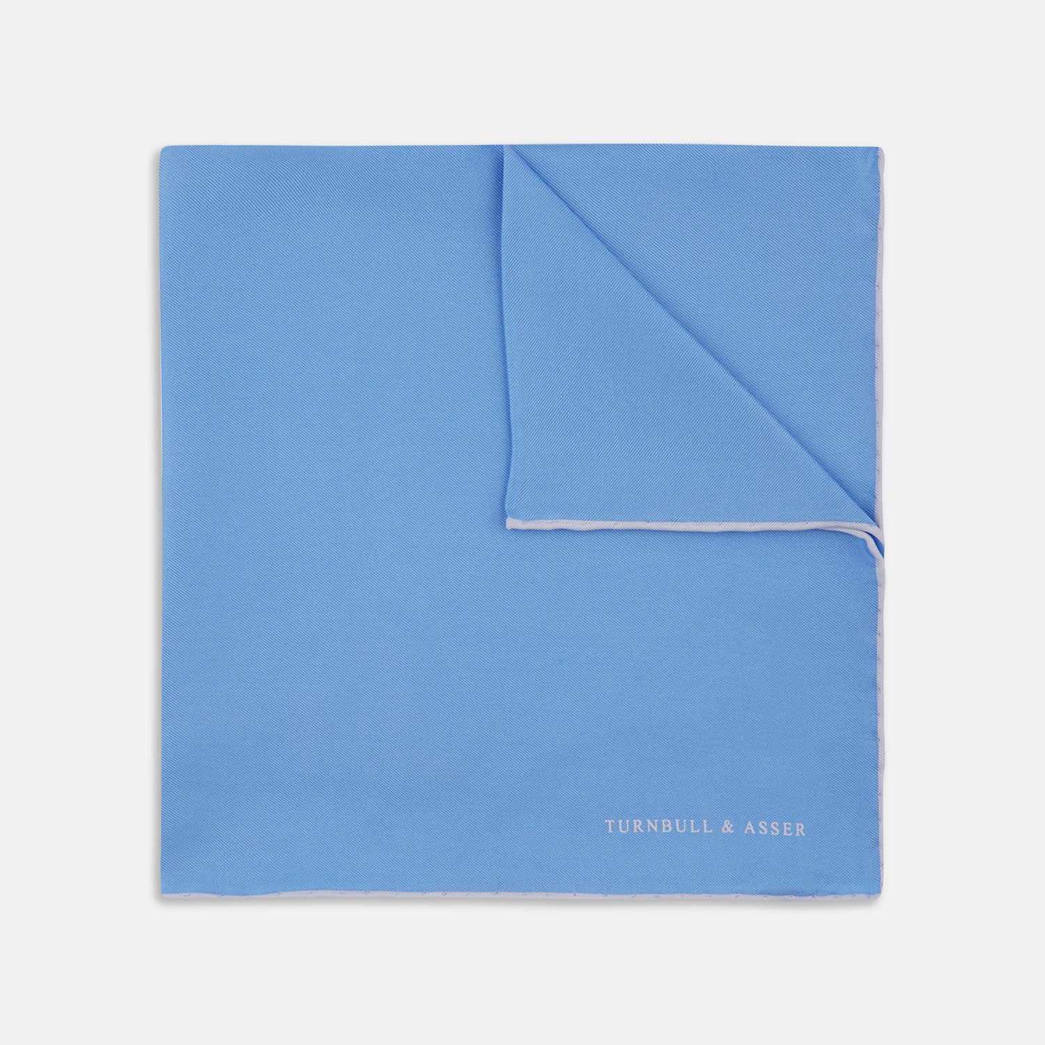 View 1 of product A Blue and White Piped Silk Pocket Square by Turnbull & Asser, neatly folded with the brand name in white on the lower right corner, displayed against a plain white background.