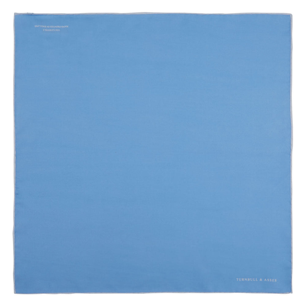 A Blue and White Piped Silk Pocket Square by Turnbull & Asser, neatly folded with the brand name in white on the lower right corner, displayed against a plain white background.