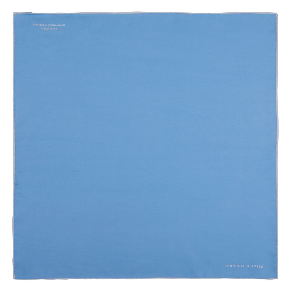 View 2 of product A Blue and White Piped Silk Pocket Square by Turnbull & Asser, neatly folded with the brand name in white on the lower right corner, displayed against a plain white background.