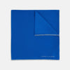 View 1 of product The Royal Blue Piped Silk Pocket Square by Turnbull & Asser features a vibrant blue hue, subtle stitched border, and the brand name printed in white in the lower right corner.