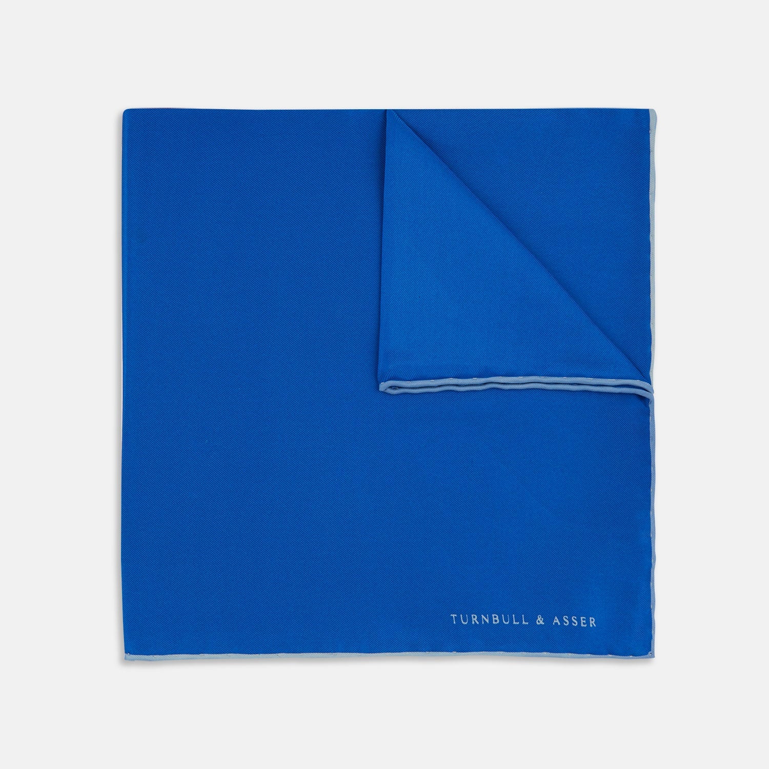 View 1 of product The Royal Blue Piped Silk Pocket Square by Turnbull & Asser features a vibrant blue hue, subtle stitched border, and the brand name printed in white in the lower right corner.