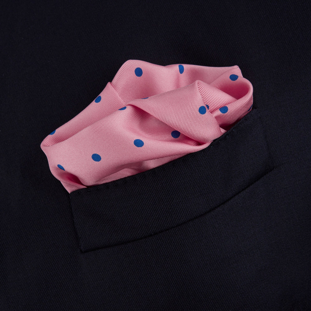 The Turnbull & Asser Rose and Blue Spot Silk Pocket Square features a pastel pink base with evenly spaced blue spots and a discreet white logo in one corner, finished with a slightly folded top for added flair.