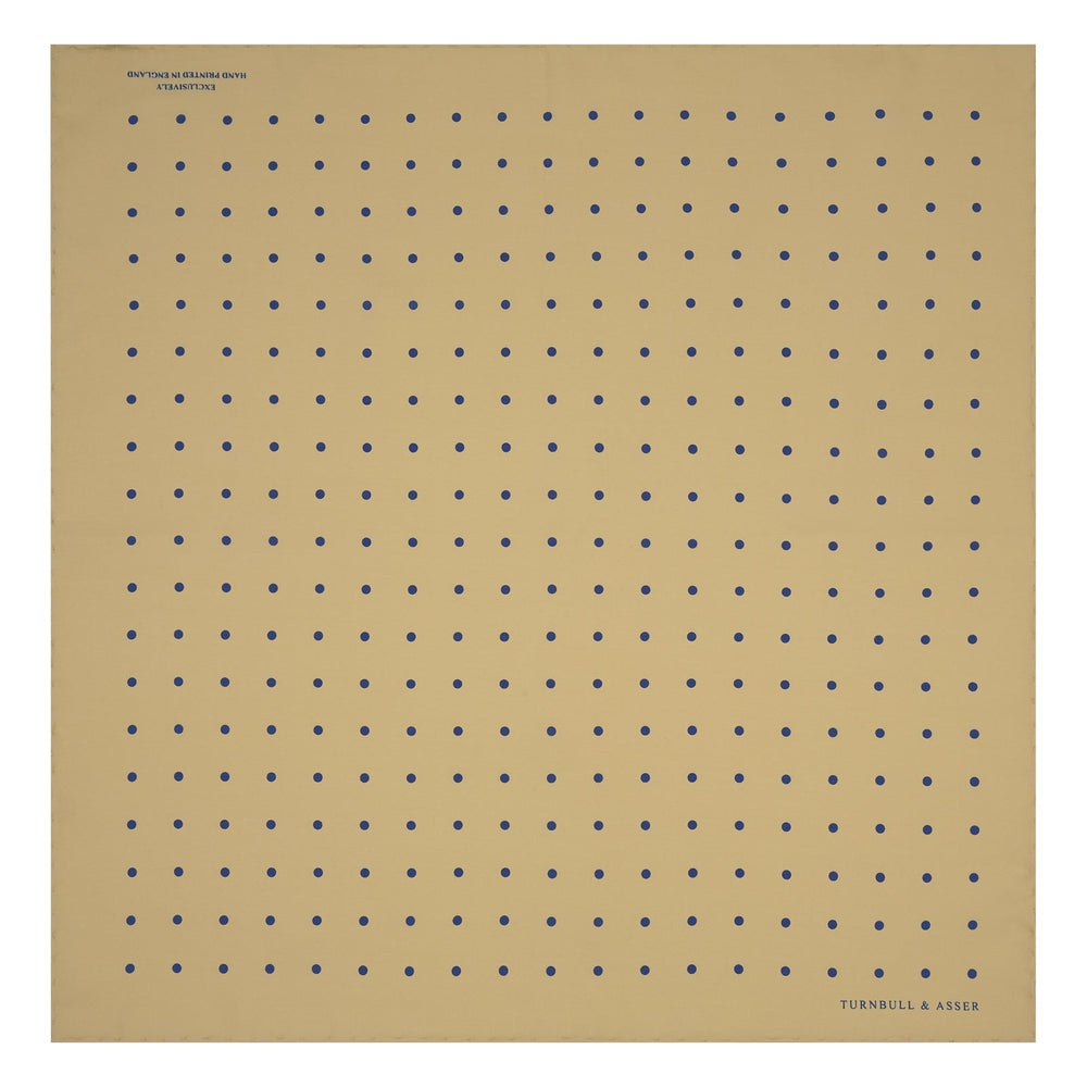 The Yellow and Blue Spot Silk Pocket Square by Turnbull & Asser features evenly spaced blue dots on yellow silk, with the brand name printed in one corner and a refined folded finish.