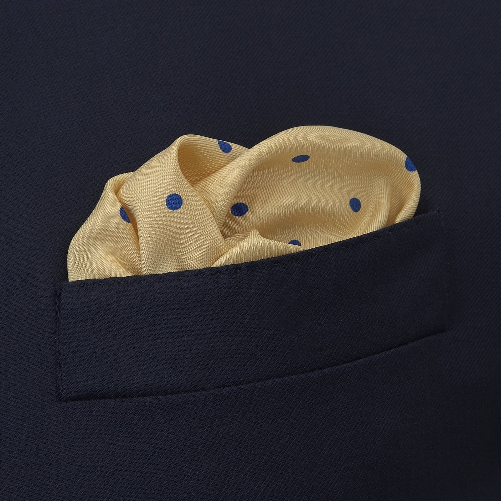 View 4 of product The Yellow and Blue Spot Silk Pocket Square by Turnbull & Asser features evenly spaced blue dots on yellow silk, with the brand name printed in one corner and a refined folded finish.