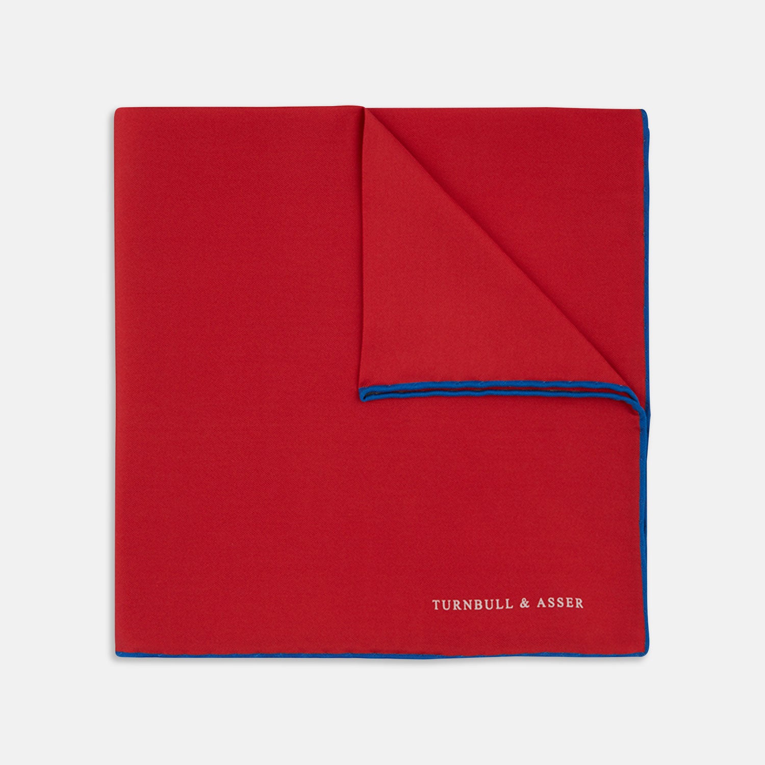 View 1 of product The Red and Navy Piped Silk Pocket Square by Turnbull & Asser features classic red silk with navy edging and the brand’s name printed in white on the bottom right corner.
