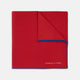The Red and Navy Piped Silk Pocket Square by Turnbull & Asser features classic red silk with navy edging and the brand’s name printed in white on the bottom right corner.