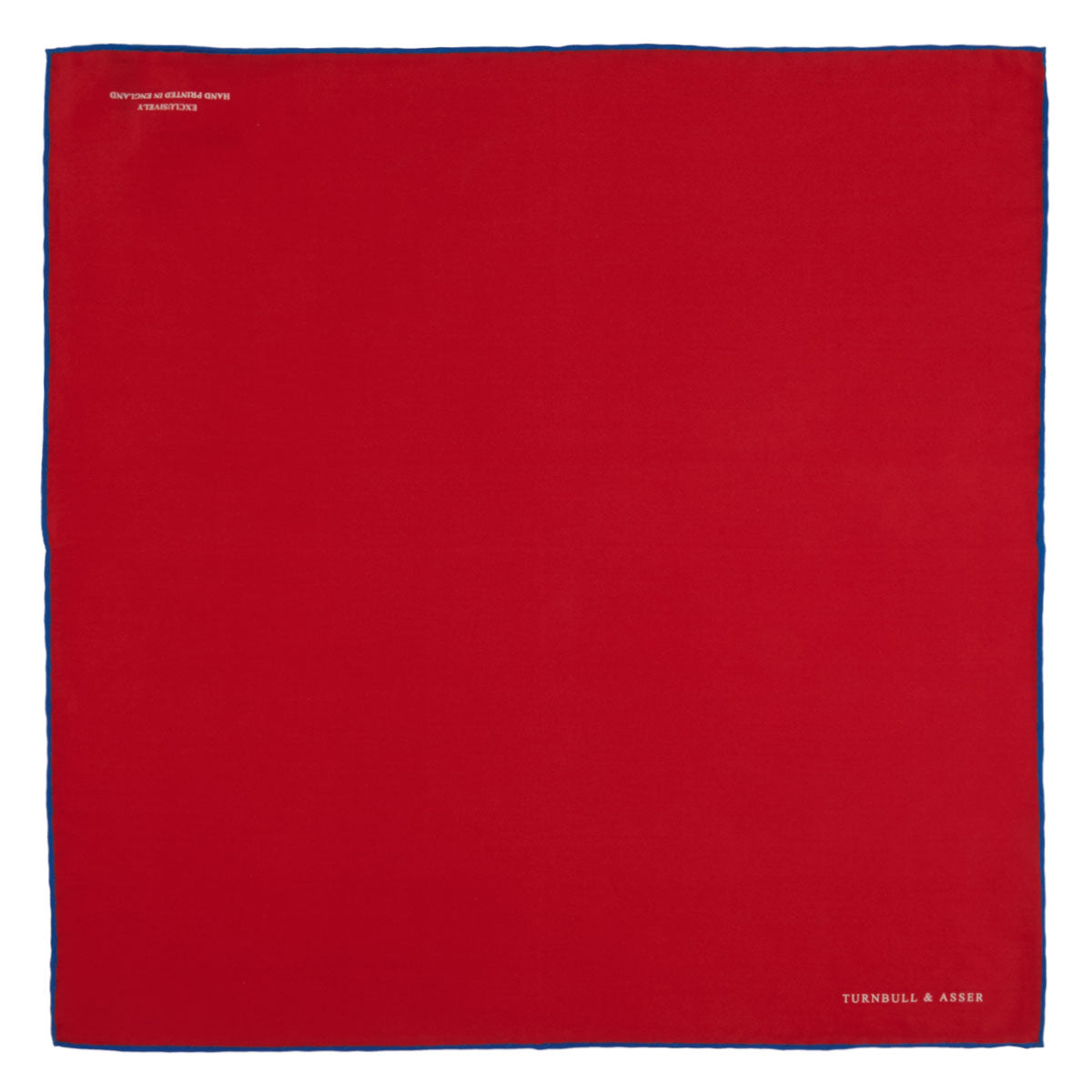 View 2 of product The Red and Navy Piped Silk Pocket Square by Turnbull & Asser features classic red silk with navy edging and the brand’s name printed in white on the bottom right corner.