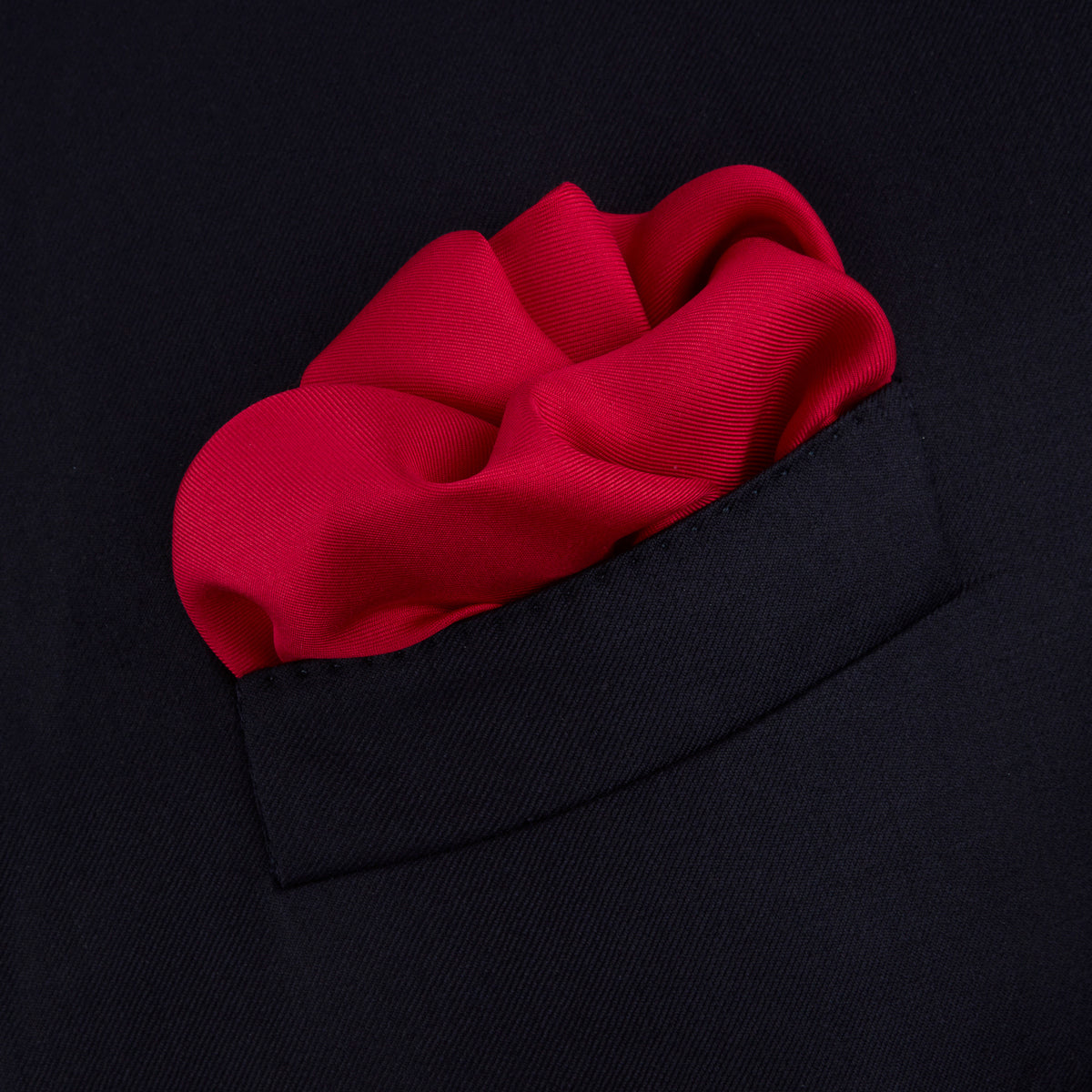 View 4 of product The Red and Navy Piped Silk Pocket Square by Turnbull & Asser features classic red silk with navy edging and the brand’s name printed in white on the bottom right corner.