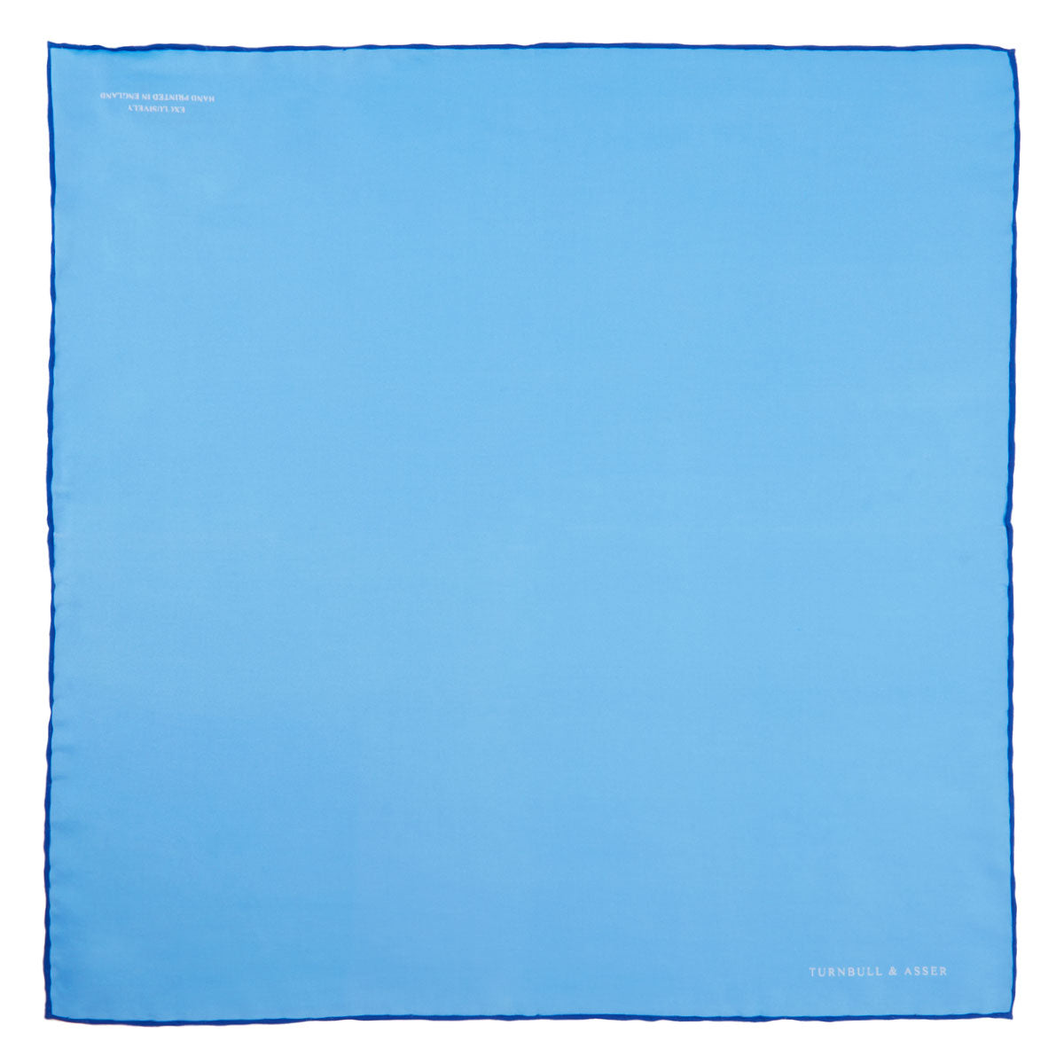 View 2 of product The Light Blue and Navy Piped Silk Pocket Square by Turnbull & Asser, neatly folded with dark blue edges and the brand’s white logo in the corner, is shown on a plain white background—a refined accessory for any occasion.