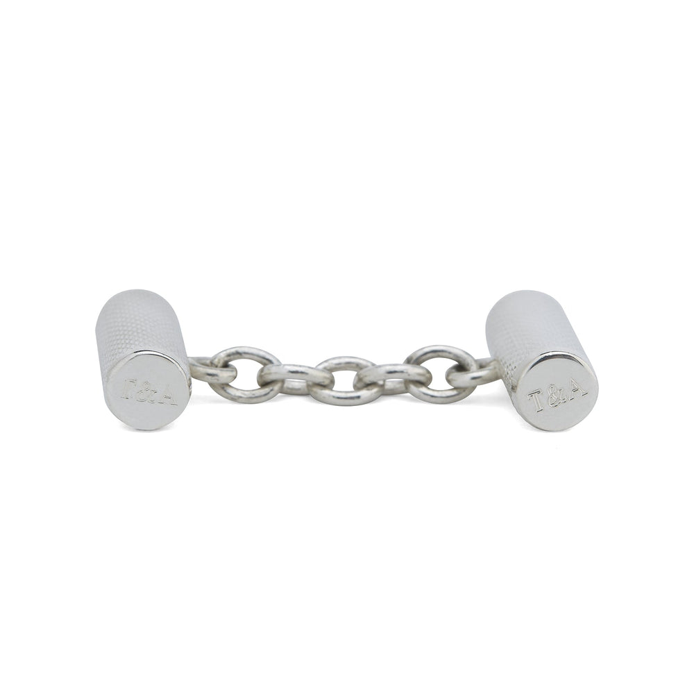 Turnbull & Asser’s Sterling Silver Bar Cufflinks feature a textured cylindrical design and chain links, making them an elegant men’s accessory, shown here on a plain white background.