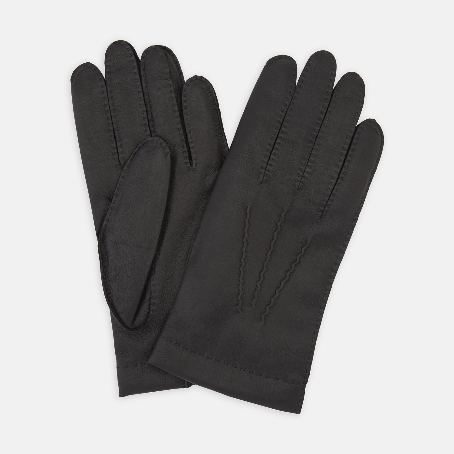 View 1 of product The Walden Black Leather Gloves by Turnbull & Asser, crafted from hairsheep leather with decorative stitching, are shown overlapping on a white background—an elegant showcase of timeless luxury and refined style.