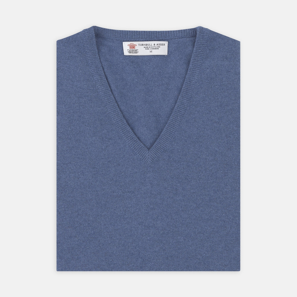 The Turnbull & Asser Blue V-Neck Cashmere Slipover, neatly folded with the label visible, is crafted from soft cashmere and ideal for formal layering. Shown against a white background.