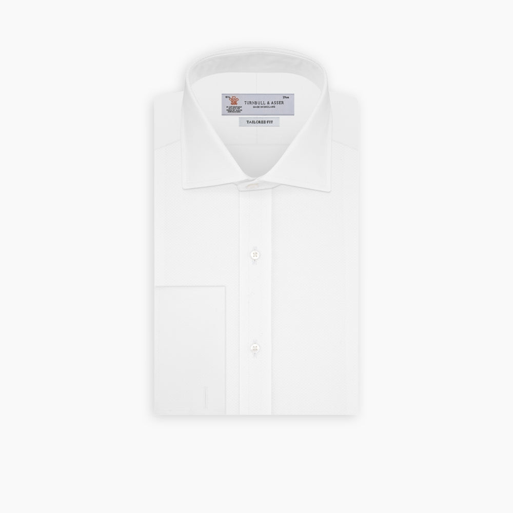 A neatly folded Turnbull & Asser Tailored Fit White Marcella Front Shirt with a Kent collar and double cuffs is displayed against a light grey background, with the label inside the collar visible.