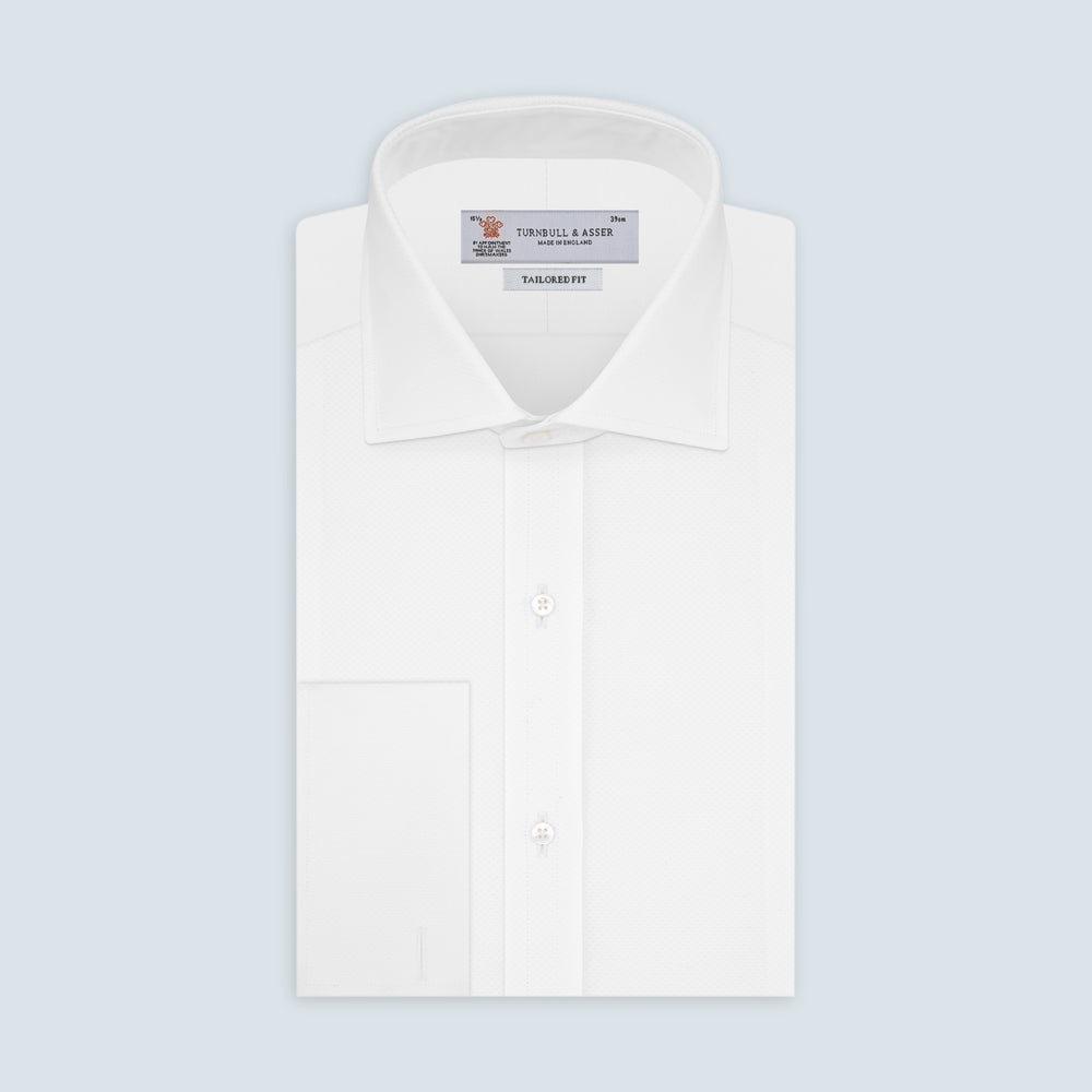 A neatly folded Turnbull & Asser Tailored Fit White Marcella Front Shirt with a Kent collar and double cuffs is displayed against a light grey background, with the label inside the collar visible.