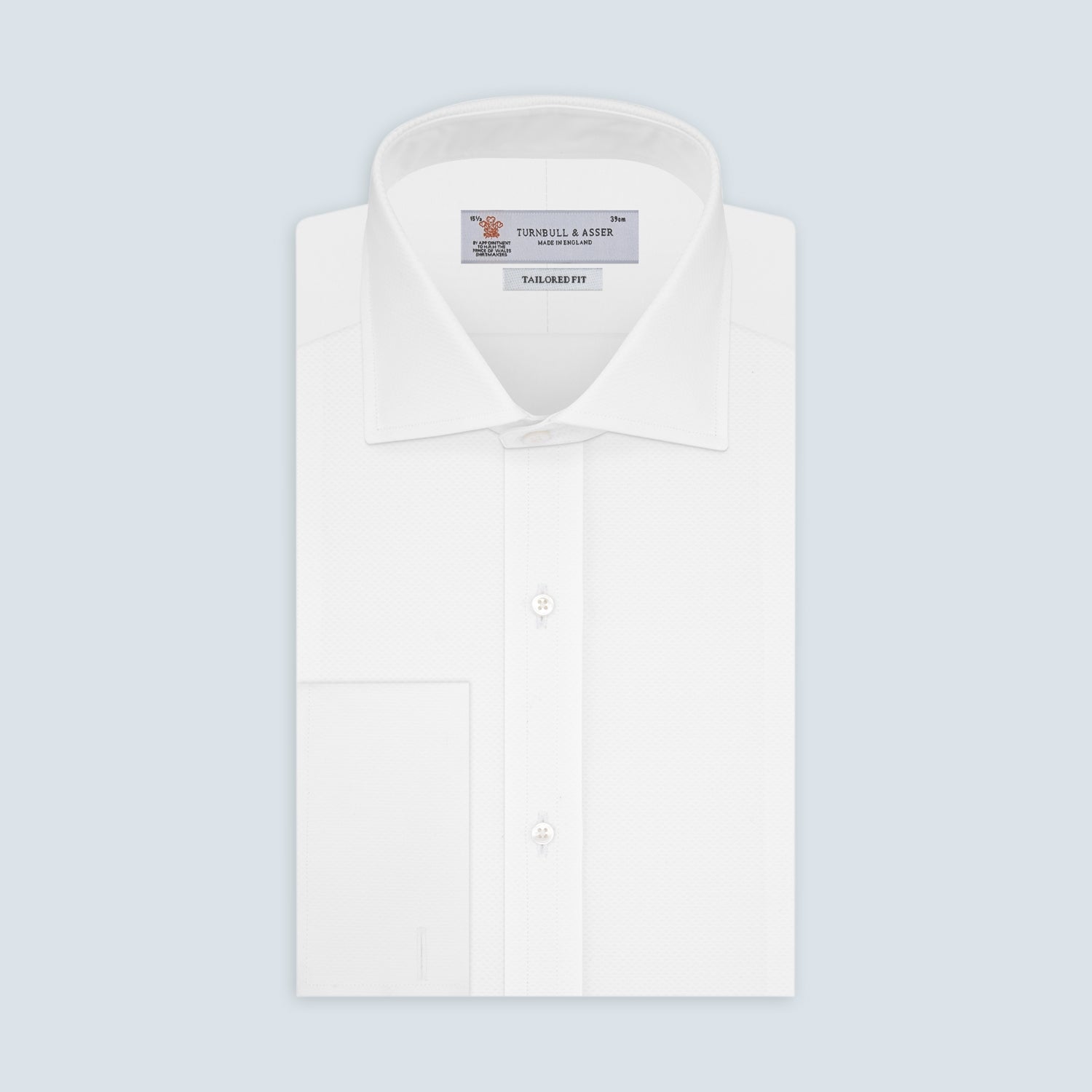 View 2 of product A neatly folded Turnbull & Asser Tailored Fit White Marcella Front Shirt with a Kent collar and double cuffs is displayed against a light grey background, with the label inside the collar visible.