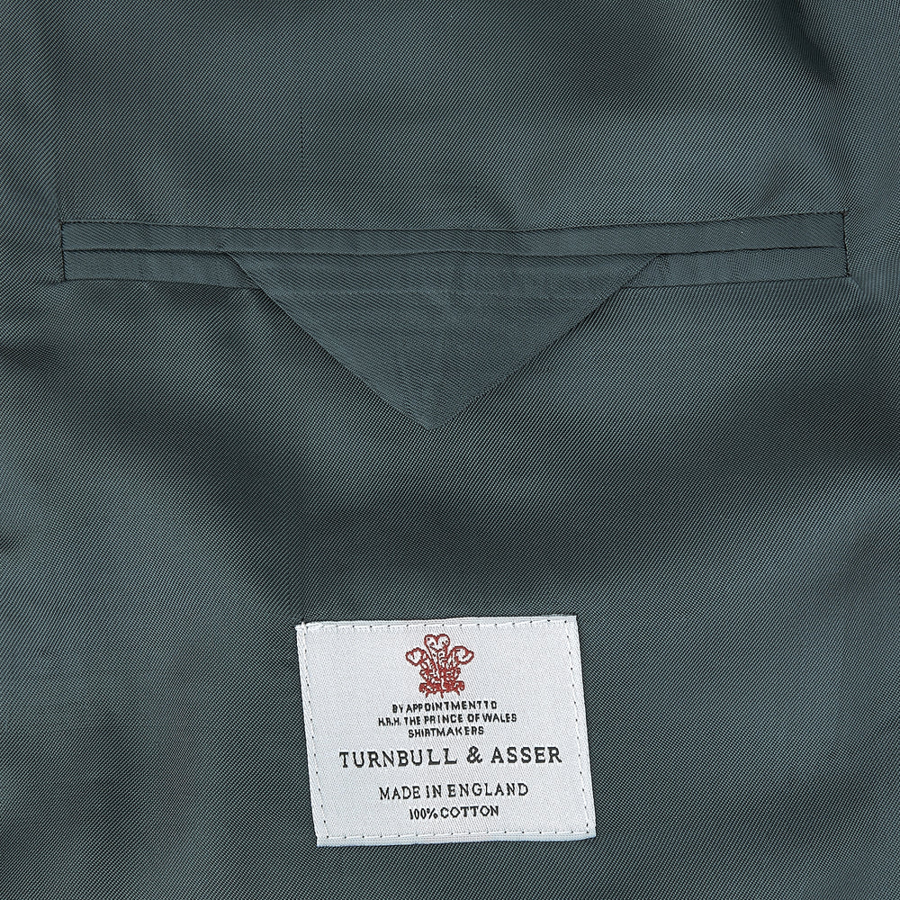 The Turnbull & Asser Green Double Breasted Velvet Smoking Jacket features a shawl collar, frog closures, and trim detailing on the cuffs and edges, shown against a white background—a sophisticated piece of eveningwear.