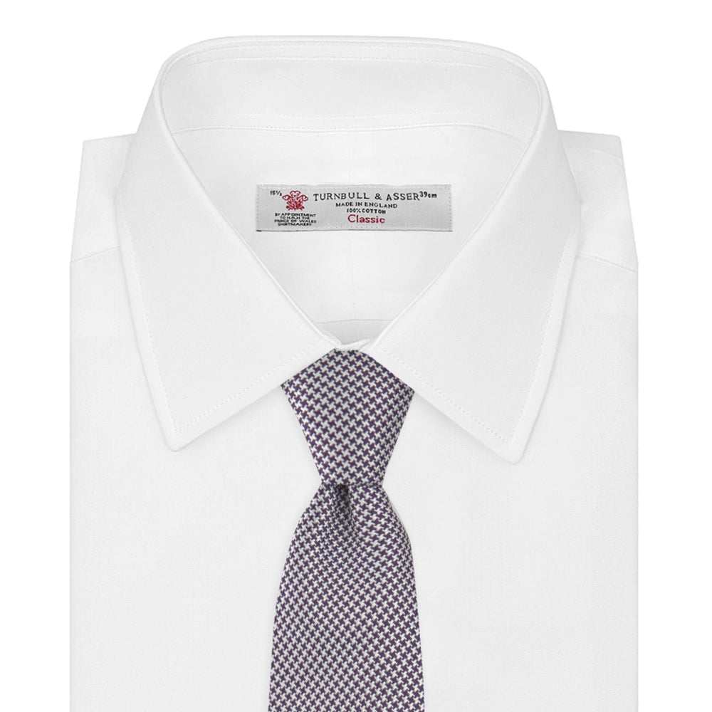The Plum Houndstooth Silk Tie by Turnbull & Asser features a refined small black, white, and gray pattern—perfect as an office shirt accessory—shown rolled up on a plain white background.