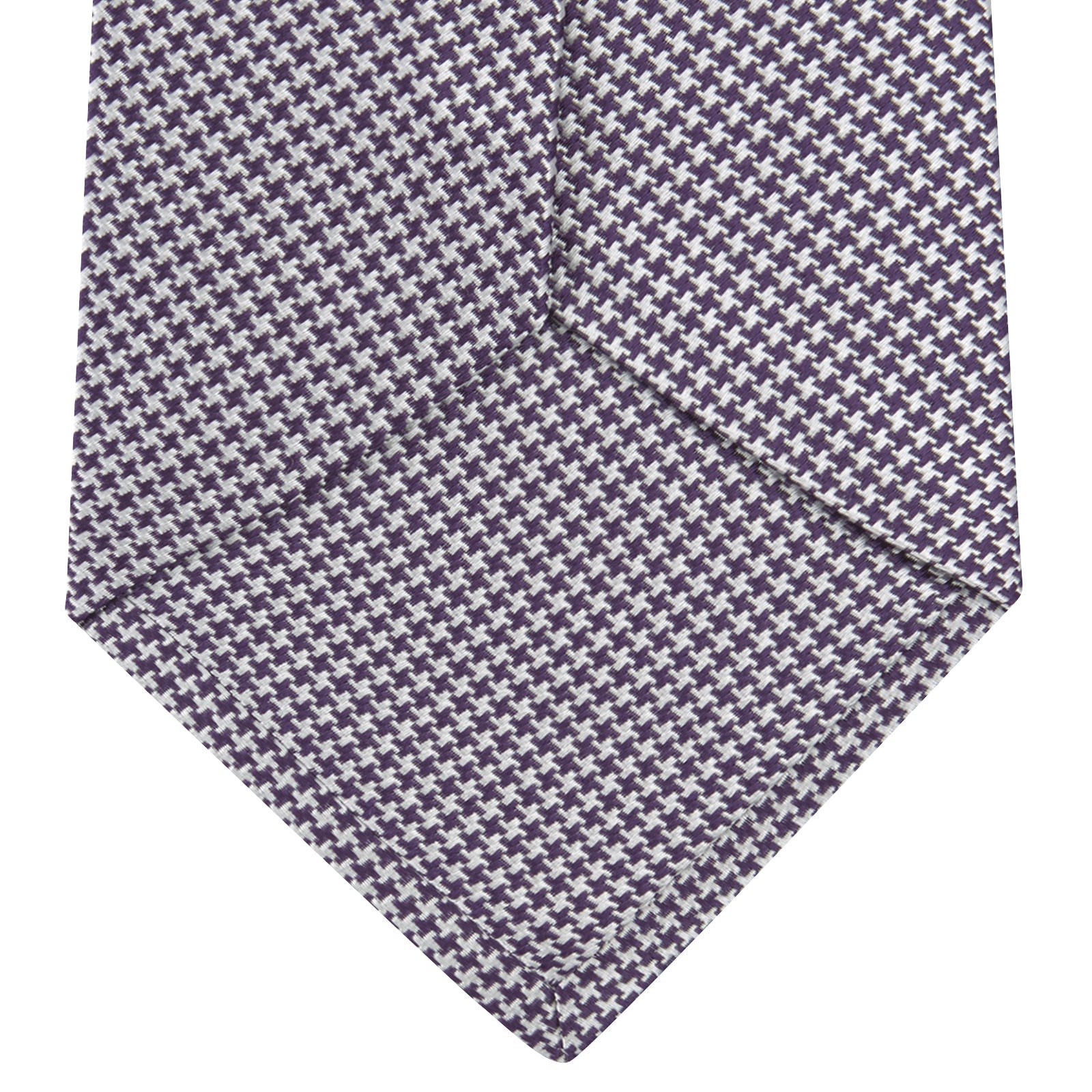 View 4 of product The Plum Houndstooth Silk Tie by Turnbull & Asser features a refined small black, white, and gray pattern—perfect as an office shirt accessory—shown rolled up on a plain white background.