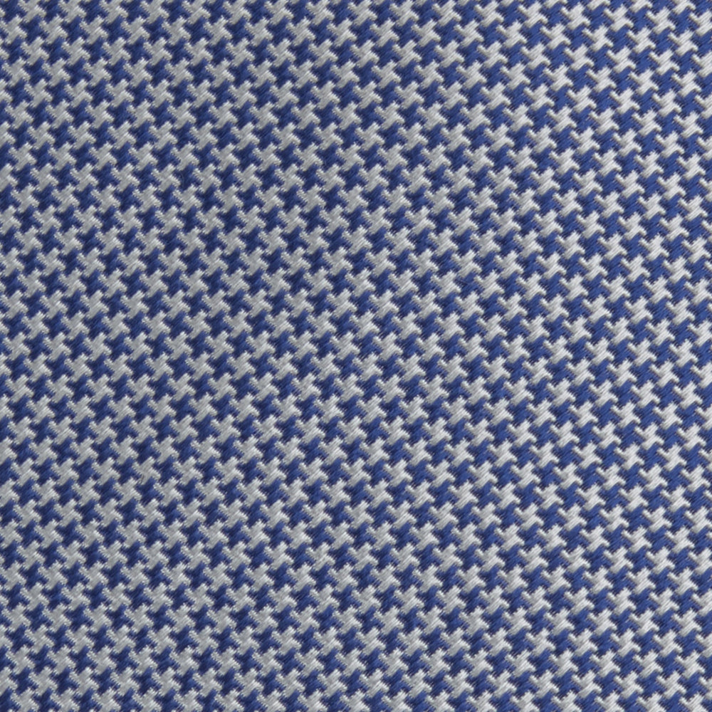 The Turnbull & Asser Blue Houndstooth Silk Tie features a classic blue and white pattern, rolled and displayed on a white background—an elegant accessory for your favorite office shirt.