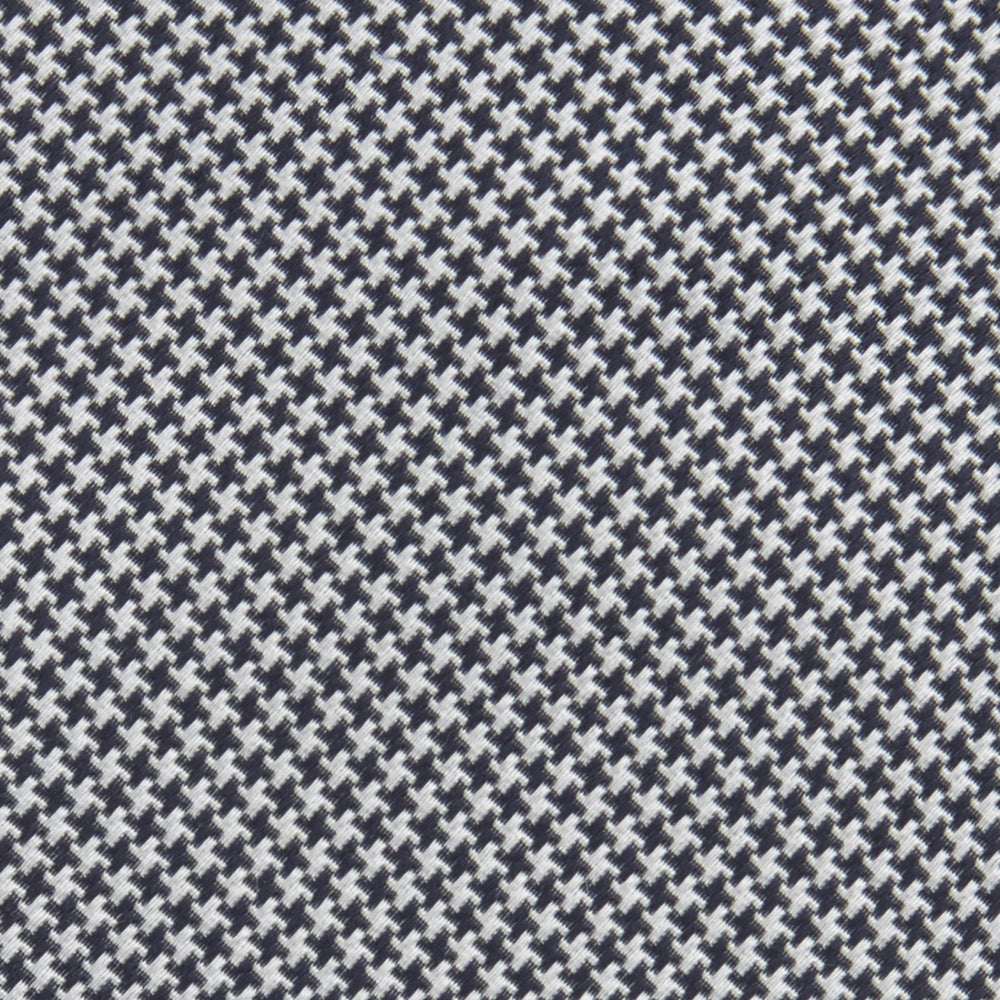 The Turnbull & Asser Navy Houndstooth Silk Tie features a refined small houndstooth pattern in navy, elegantly rolled and showcased on a white background.