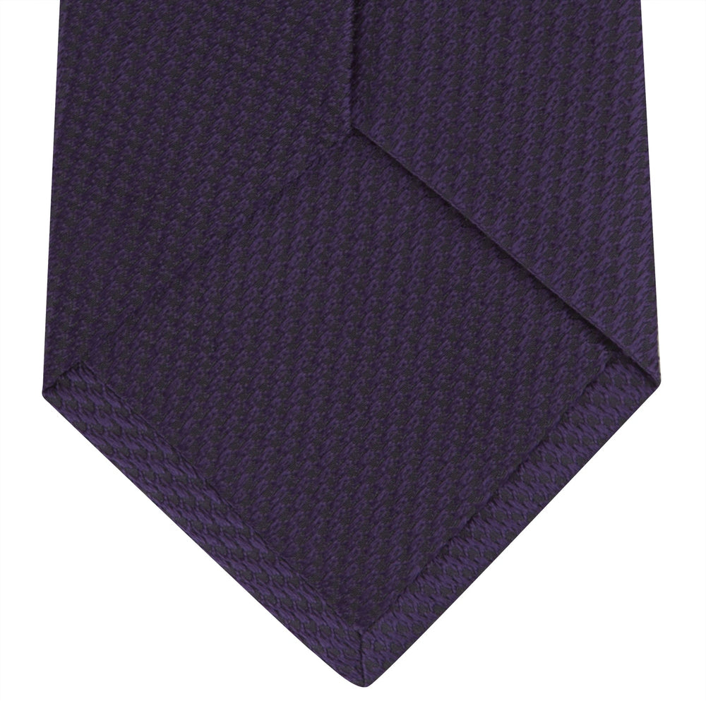 The Turnbull & Asser Plum Lace Silk Tie features a neatly rolled, dark purple design with a textured finish, displayed on a plain white background.