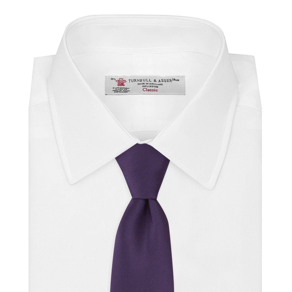 The Turnbull & Asser Plum Plain Satin Silk Tie, shown rolled up on a white background, highlights its classic and versatile style for any occasion.