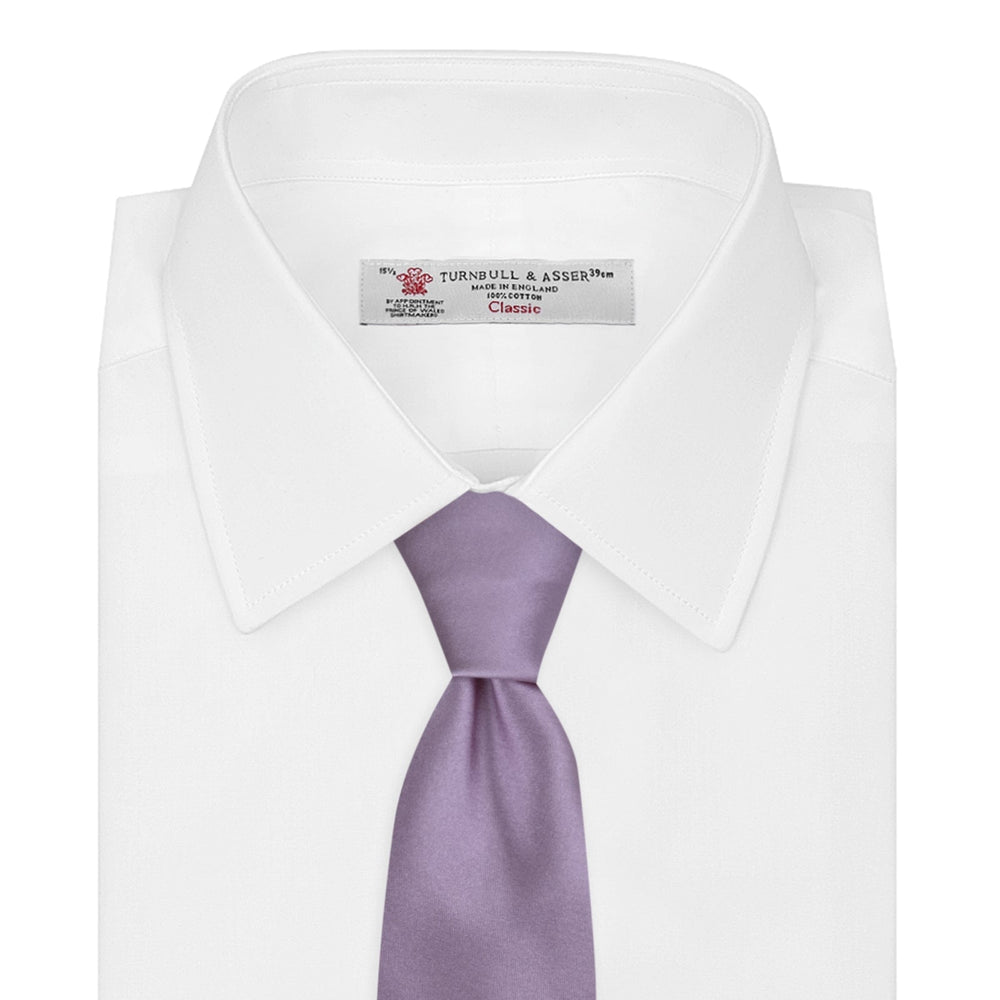 The Turnbull & Asser Lilac Plain Satin Silk Tie, featuring a smooth finish, is neatly rolled and displayed on a white background—a classic accessory for any versatile wardrobe.