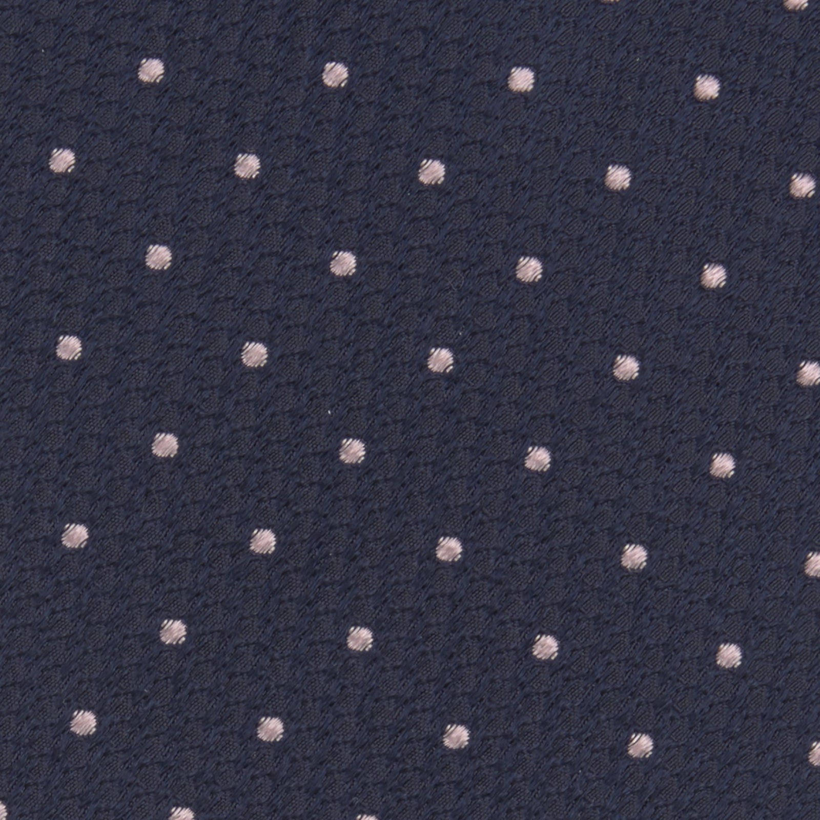 View 3 of product The Turnbull & Asser Navy and Rose Spot Lace Silk Tie features a rolled-up navy design with delicate rose spots, ideal for adding elegance to any office shirt, shown against a plain white background.
