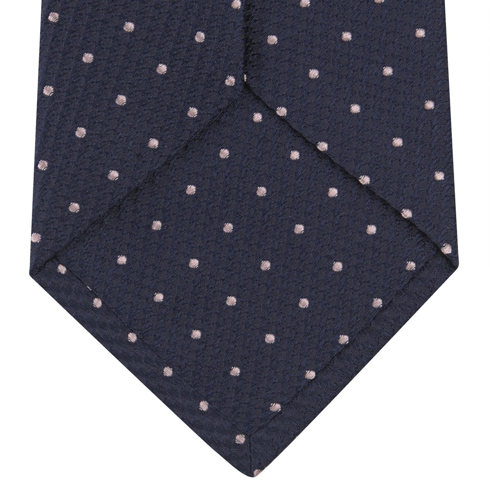 The Turnbull & Asser Navy and Rose Spot Lace Silk Tie features a rolled-up navy design with delicate rose spots, ideal for adding elegance to any office shirt, shown against a plain white background.