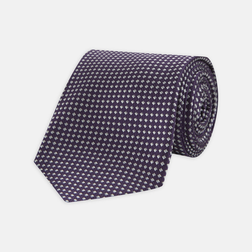 The Turnbull & Asser Plum and White Diamond Silk Tie features a subtle repeating pattern, shown rolled up on a white background—a timeless accessory to elevate any office shirt.