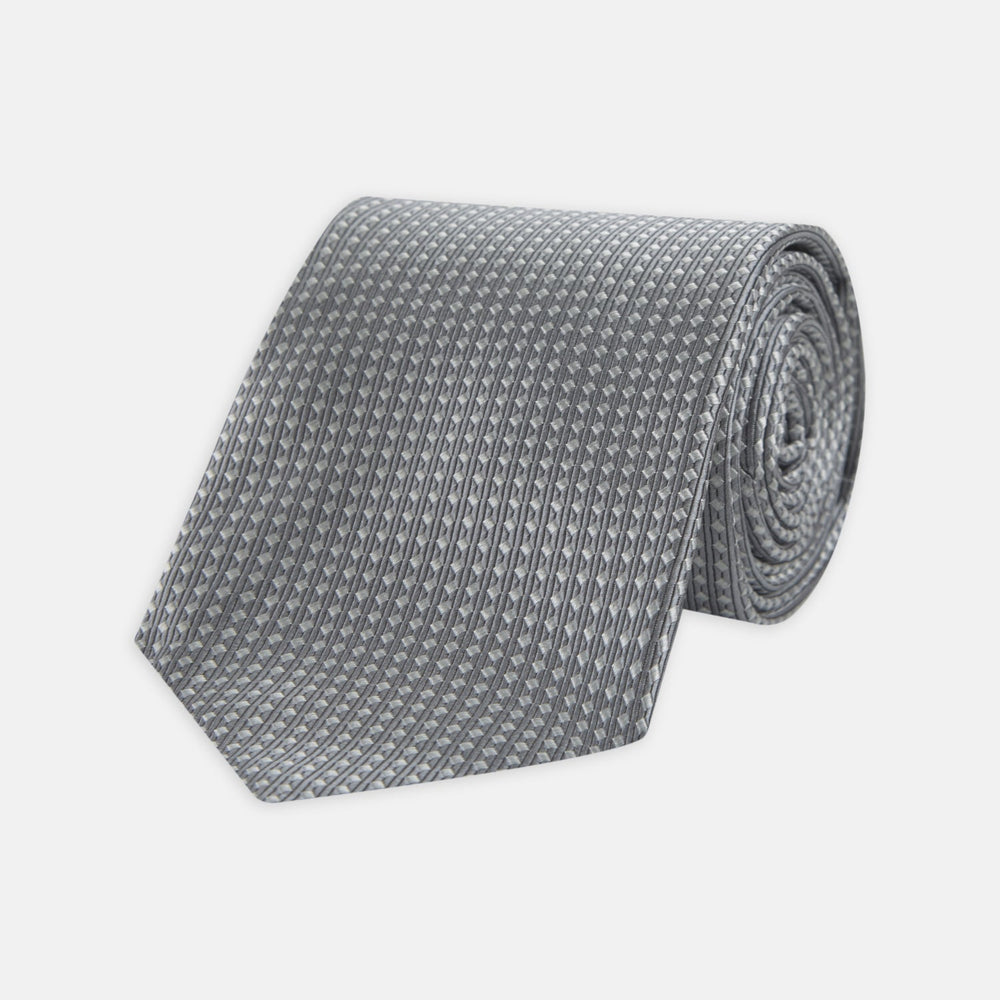 The Turnbull & Asser Grey and White Diamond Silk Tie, featuring a subtle textured pattern, is perfect for pairing with an office shirt and is displayed against a white background.
