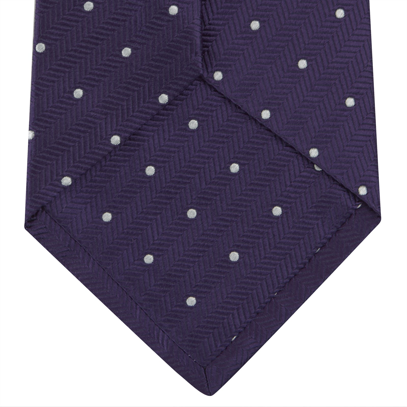 View 4 of product The Turnbull & Asser Plum and White Small Spot Herringbone Silk Tie is shown rolled up on a plain white background, featuring a classic silk herringbone weave in plum with small white spots.