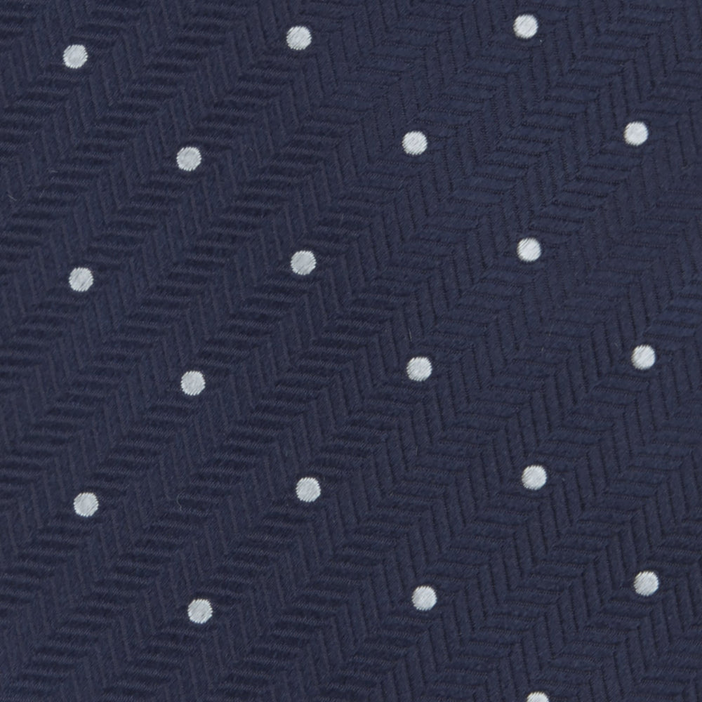 The Navy and White Small Spot Herringbone Silk Tie from Turnbull & Asser features a classic navy herringbone pattern with small white polka dots, offering an elegant look suitable for any occasion.