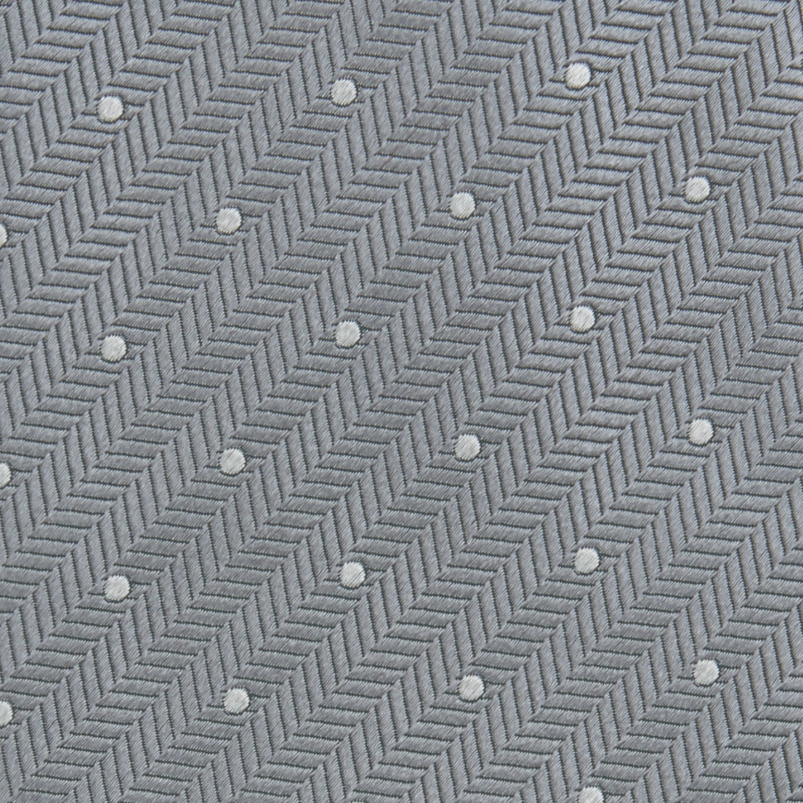 View 3 of product The Turnbull & Asser Grey and White Small Spot Herringbone Silk Tie, expertly woven from silk, is displayed rolled-up against a white background.