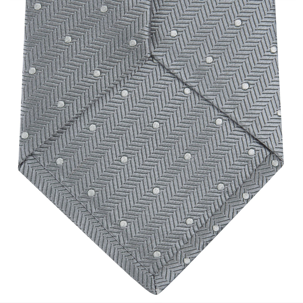 The Turnbull & Asser Grey and White Small Spot Herringbone Silk Tie, expertly woven from silk, is displayed rolled-up against a white background.
