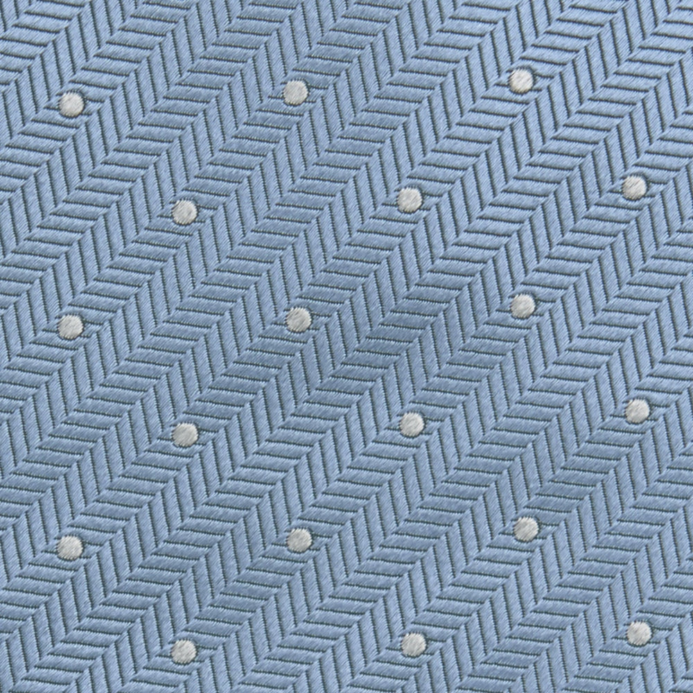 The Turnbull & Asser Ice Blue and White Small Spot Herringbone Silk Tie features a refined herringbone weave with subtle white spots, displayed elegantly against a plain white background.