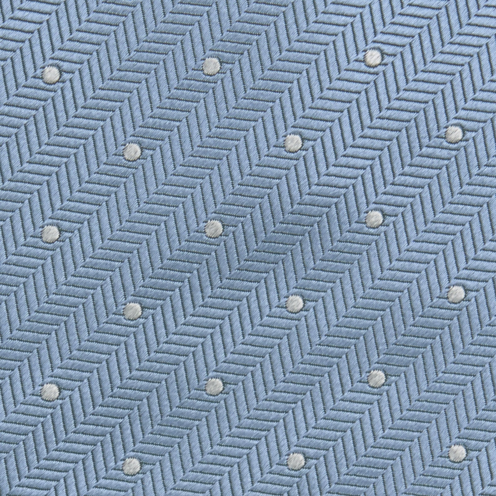 View 3 of product The Turnbull & Asser Ice Blue and White Small Spot Herringbone Silk Tie features a refined herringbone weave with subtle white spots, displayed elegantly against a plain white background.