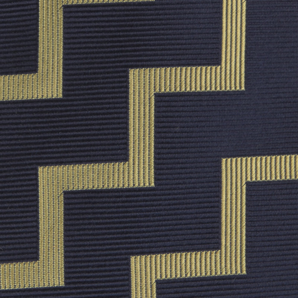 The Navy and Gold Striped Zigzag Silk Tie by Turnbull & Asser features a bold geometric pattern—an essential modern accessory shown rolled up with the pointed end forward on a white background.