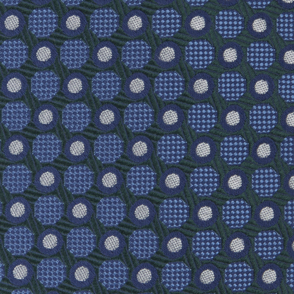 Turnbull & Asser’s Forest Green and Blue Circle and Spot Silk Tie, rolled on a white background, features a refined pattern—an elegant classic for any office shirt.